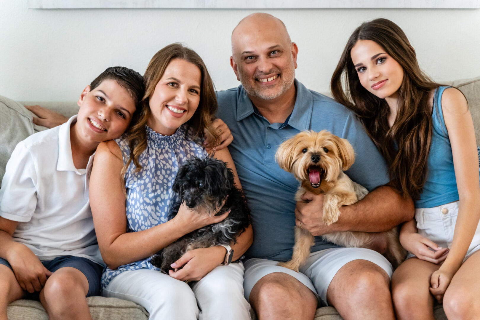 A family of four with two dogs sitting on the couch.